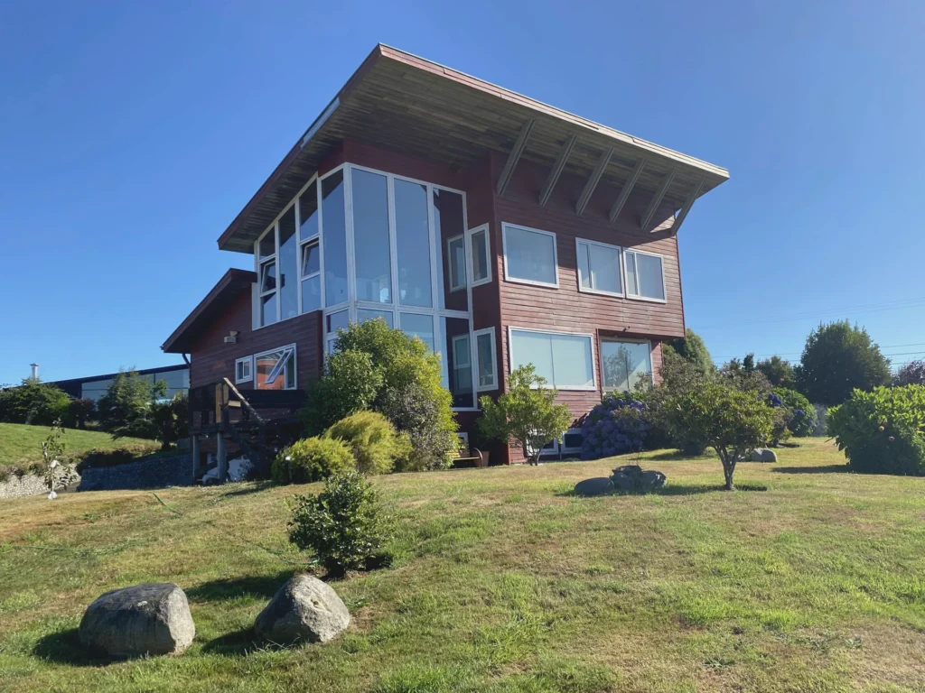 Exterior de Casa Mirador, su volumen vertical, ventanales y jardín.