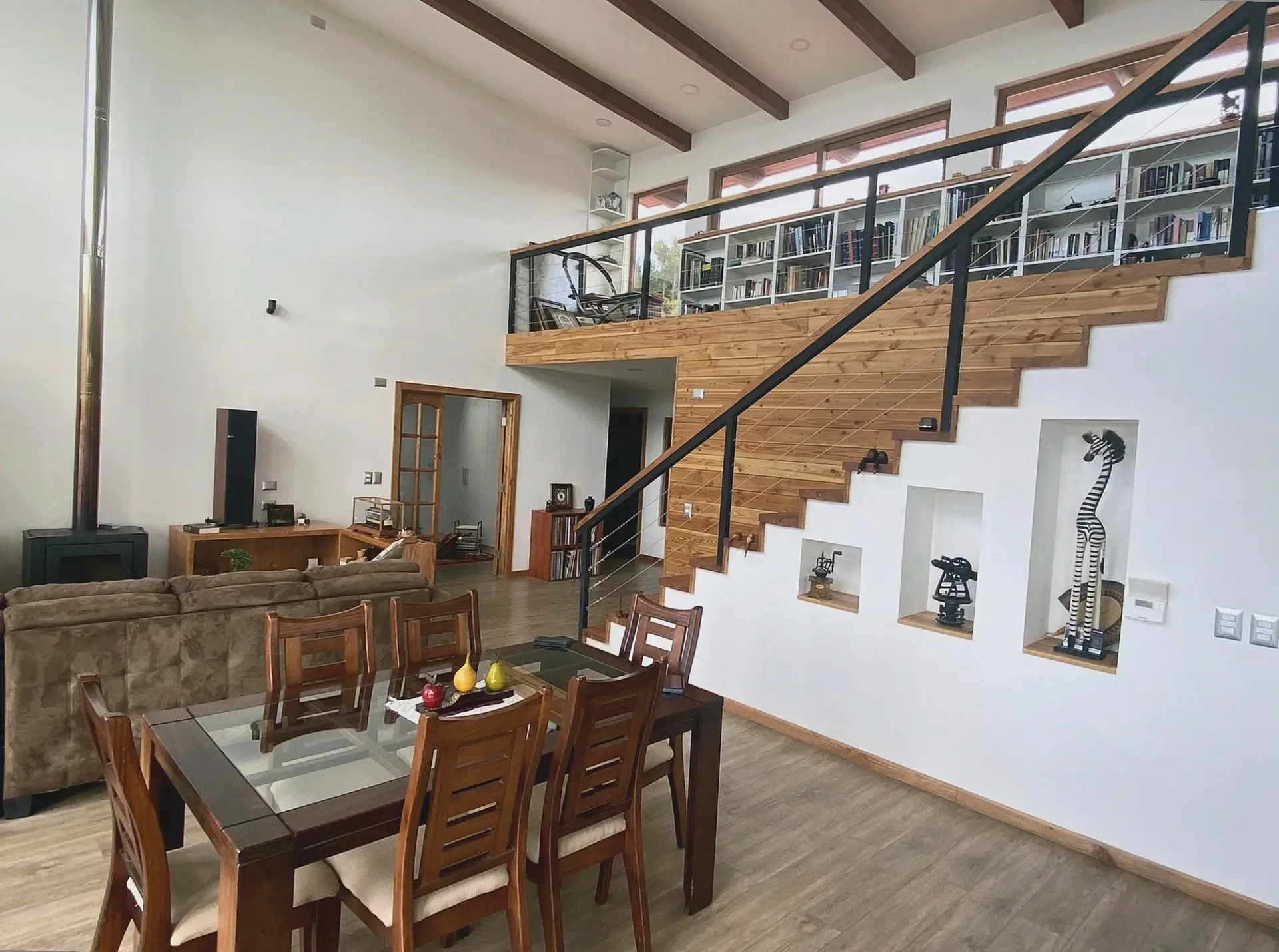 Interior de Casa PULT, con doble altura, escalera, comedor y pasarela.