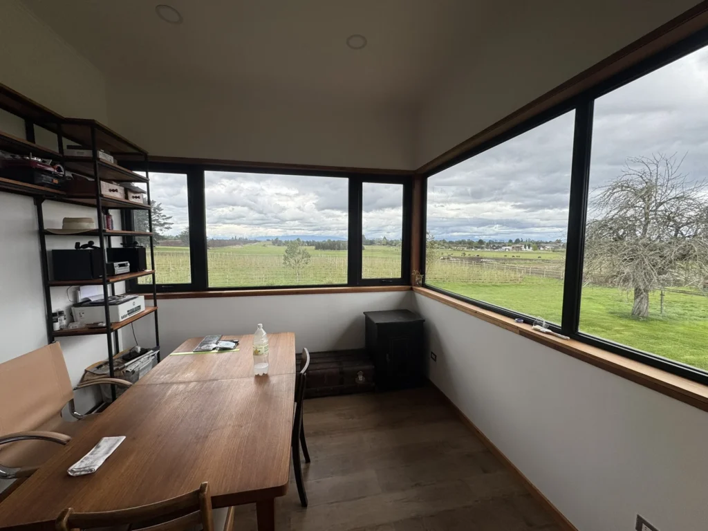 Espacio de trabajo con ventanales en dos fachadas hacia el paisaje rural.